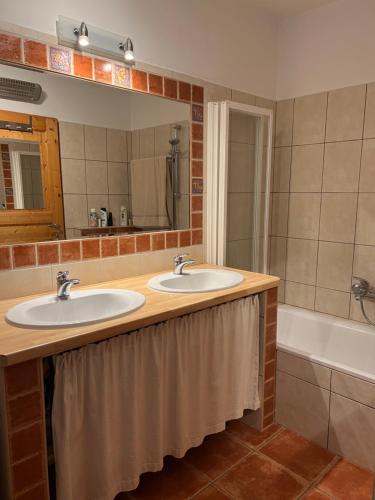uma casa de banho com 2 lavatórios, uma banheira e um espelho. em Haus Karner em Neusiedl am See