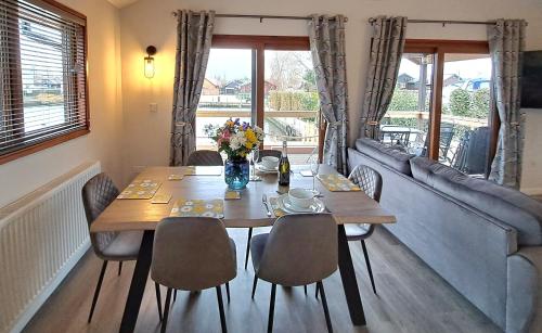 a dining room with a table and chairs and a couch at River Breeze - Norfolk Broads in Brundall