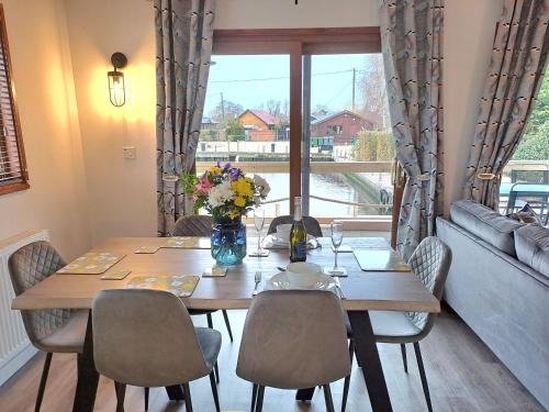 a dining room table with chairs and a large window at River Breeze - Norfolk Broads in Brundall