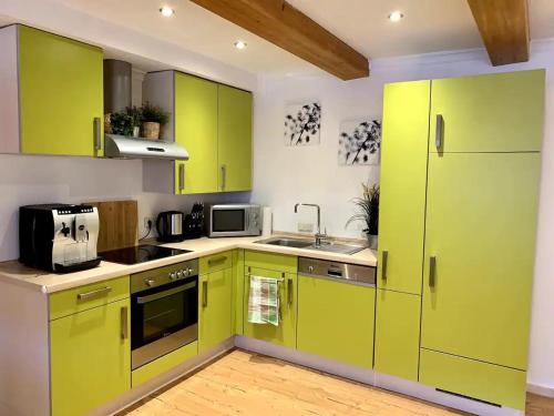 - une cuisine avec des armoires vert citron et un évier dans l'établissement Ferienwohnung Vierseithof, à Eging am See