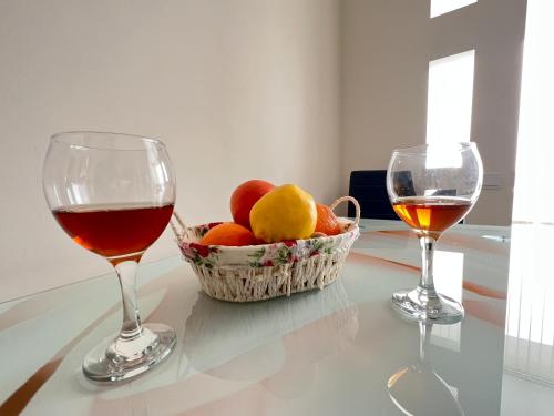 two glasses of wine and a basket of fruit on a table at English Breakfast in Chişinău