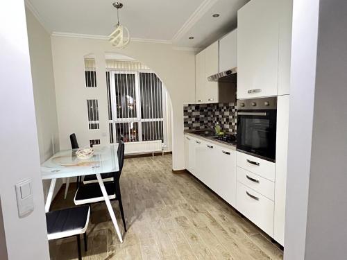 a kitchen with white cabinets and a table and a microwave at English Breakfast in Chişinău
