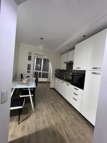 a kitchen with white cabinets and a dining table at English Breakfast in Chişinău