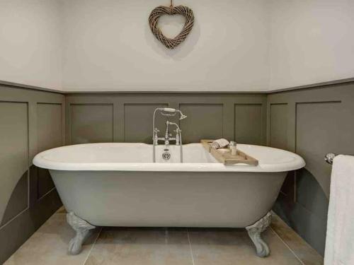a white bath tub in a bathroom with a heart decoration at Dovecote in Chipping Campden