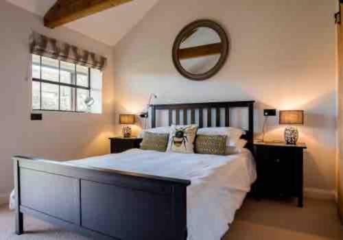 a bedroom with a large bed and a mirror at Dovecote in Chipping Campden