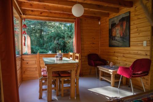 comedor con mesa, sillas y ventana en BOG Budas del Bosque en Villa La Angostura