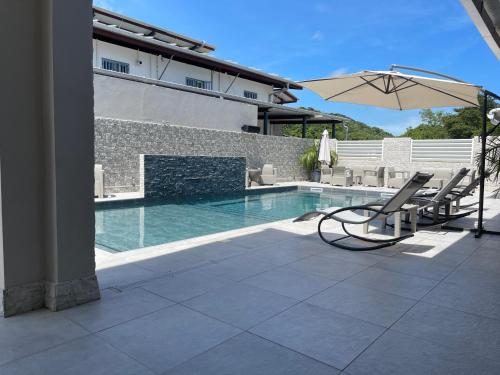 a patio with an umbrella and chairs and a pool at Relax Appart Hôtel in Kourou