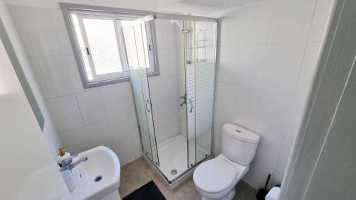 een witte badkamer met een douche en een toilet bij Modern Retreat: 2br Stylish Apt with Comfy Rooms! Smart TV with 200MBPS Internet in Larnaka