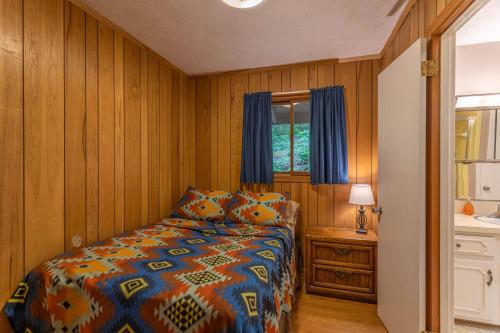 1 dormitorio con 1 cama con cortinas azules y ventana en Bucky's Hideaway, en Todd