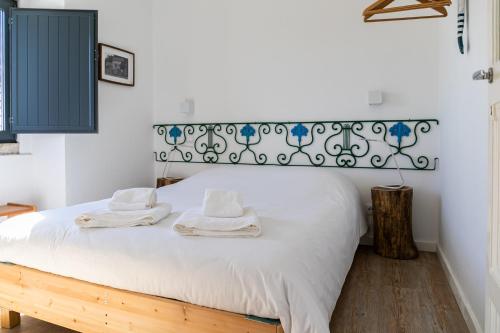 Un dormitorio con una cama blanca con toallas. en Casota - Lusitália Eden, en Sintra