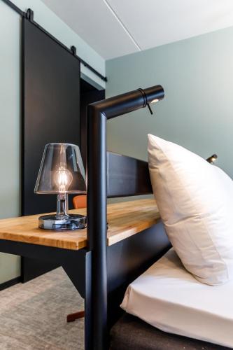 a bed and a desk with a lamp and a bed sidx sidx sidx at Hotel Valkenburg by Mercure - Next to Shimano Experience Center in Valkenburg