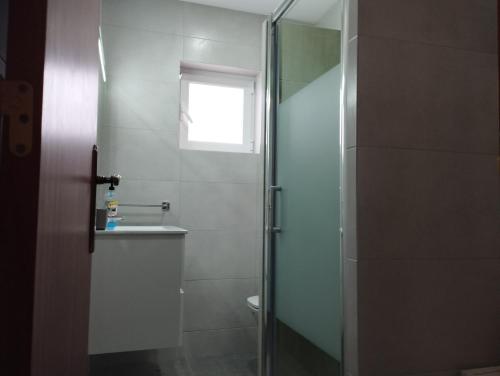 uma casa de banho com um chuveiro, um WC e uma janela. em Casa Barrela I em Tavira