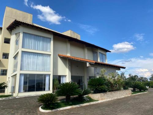 a white building with palm trees in front of it at Class Hotel Passos Rio Grande Portal da Canastra in Passos