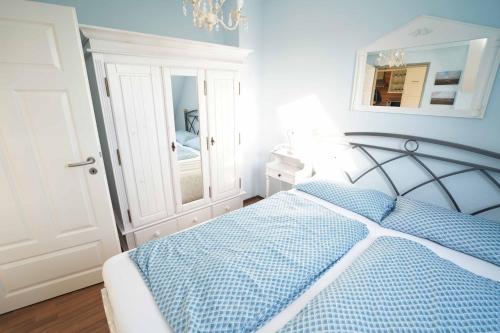 Schlafzimmer mit einem blauen und weißen Bett und einem Spiegel in der Unterkunft Ferienwohnung Sonne&Meer in Dornum