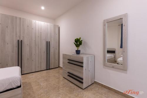 a bedroom with a dresser and a mirror at Gozo - Apartment with Stunning Views & Shared Pool in Xagħra