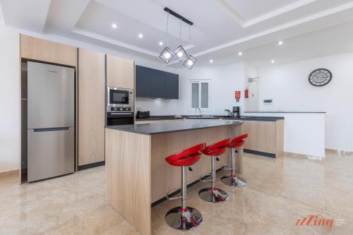 a kitchen with a counter and red stools in it at Gozo - Apartment with Stunning Views & Shared Pool in Xagħra