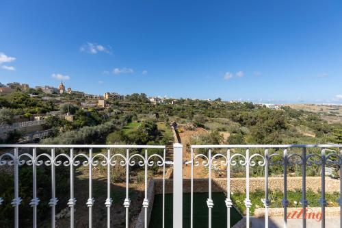 a fence with a view of a hill at Gozo - Apartment with Stunning Views & Shared Pool in Xagħra