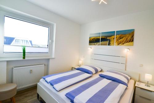 a white bedroom with two beds and a window at Am Sahlenburger Strand AS01 in Cuxhaven