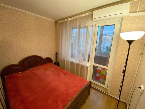 1 dormitorio con cama roja y ventana en Центр 3 слободская, en Mykolaiv