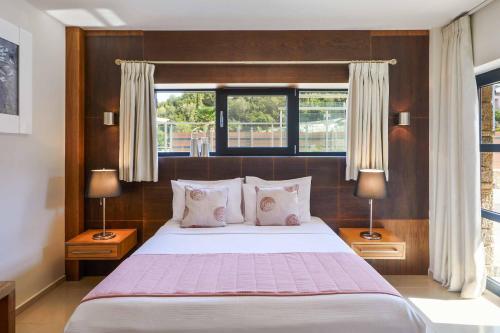 una camera da letto con un grande letto con due lampade e una finestra di Villa Michael Karvouno Villas a Sivota