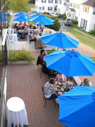a group of people sitting at tables with blue umbrellas at Atlantic Oceanside Hotel & Conference Center in Bar Harbor