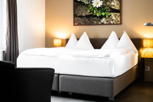 um quarto de hotel com uma cama grande com almofadas brancas em Alpenblick Weggis - Panorama & Alpen Chic Hotel em Weggis