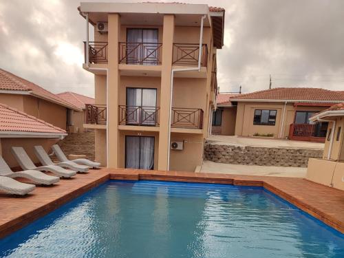 uma casa com piscina em frente a um edifício em Coastal Beach Resort em Umkomaas