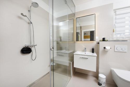 a white bathroom with a shower and a sink at Zadar Sunset Penthouse with spectacular view and jacuzzi in Zadar