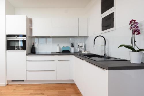 a white kitchen with white cabinets and a sink at Zadar Sunset Penthouse with spectacular view and jacuzzi in Zadar