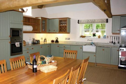 a kitchen with a wooden table with a bottle of wine at Groves Barn at Norton Grounds in Chipping Campden