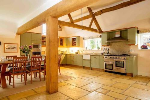 una cocina con armarios verdes, mesa y sillas en Groves Barn at Norton Grounds, en Chipping Campden