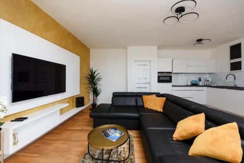 a living room with a black leather couch and a flat screen tv at Zadar Sunset Penthouse with spectacular view and jacuzzi in Zadar