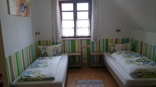 two beds in a small room with a window at Pension Zur Sonne Wittenweier in Schwanau