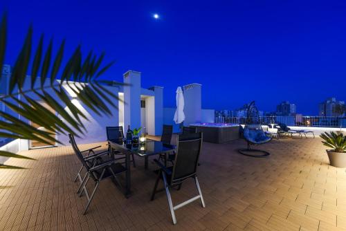 a rooftop patio with a table and chairs at night at Zadar Sunset Penthouse with spectacular view and jacuzzi in Zadar