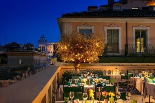 un grupo de mesas y sillas en un balcón por la noche en Singer Palace Hotel, en Roma