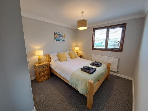 a bedroom with a bed and two lamps and a window at River Retreat - Norfolk Broads in Brundall