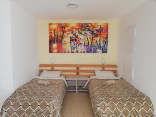 - une chambre avec 2 lits et un tableau mural dans l'établissement Desert Sunrise Arad, à Arad