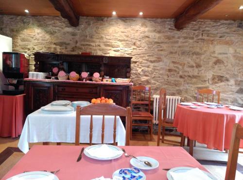 a dining room with two tables and a stone wall at PR San Nicolás in Santiago de Compostela