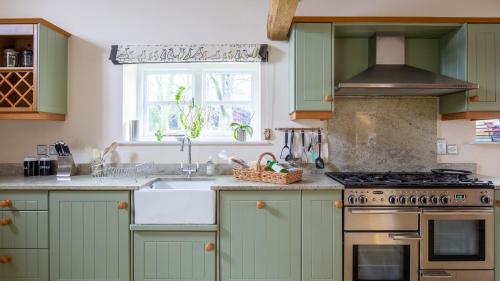 a kitchen with green cabinets and a sink at Groves Barn at Norton Grounds in Chipping Campden