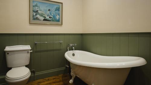 a bathroom with a tub and a toilet and a sink at Groves Barn at Norton Grounds in Chipping Campden