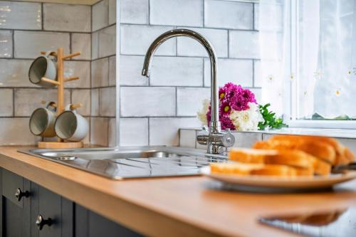 a kitchen counter with a sink and a plate of bread at Finest Retreats - Tyg Cottage near Masham, Fountains Abbey & Brimham Rocks in Ripon