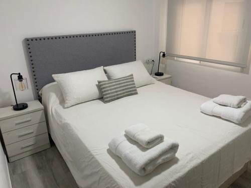 sypialnia z białym łóżkiem i ręcznikami w obiekcie Absolu Almansa w Maladze