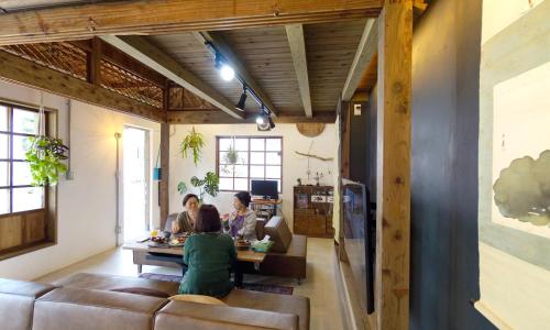 un grupo de personas sentadas en una mesa en una sala de estar en ロフトが付いた沖縄古民家で寛ぎの時間を 懐かしくて新しい 海野24, en Nanjō