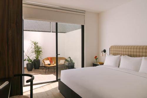 1 dormitorio con cama blanca y balcón en Sonder Aria, en Ciudad de México