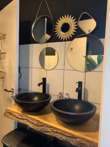 Baño con 2 lavabos negros en una encimera con espejos en Luxe in stiltegebied tussen loslopende Alpaca’s, 