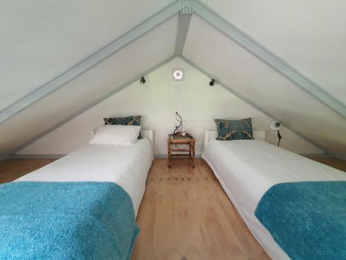 two beds in a room with a roof at Beautiful garden cottage in Stormsrivier