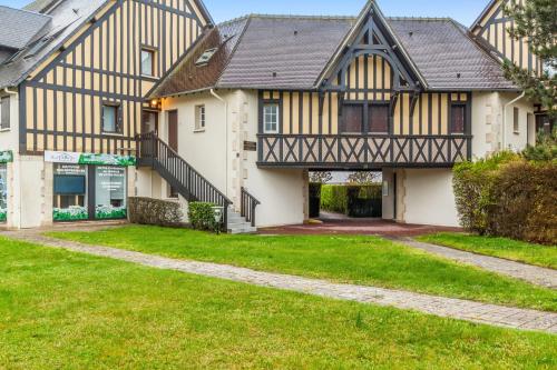 une maison avec une pelouse verte devant elle dans l'établissement Appartement Cassulo - Welkeys, à Cabourg