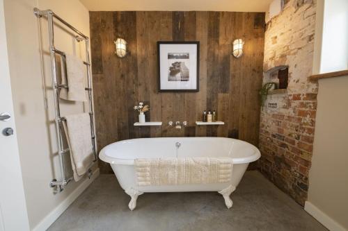 bagno con vasca bianca e parete in mattoni di Flittermouse Barn a Goxhill