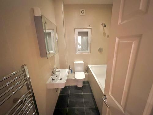 a bathroom with a sink and a toilet and a tub at Spacious 2 bedroom apartment in London