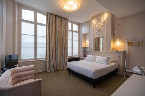 sypialnia z łóżkiem, krzesłem i oknami w obiekcie Hôtel Loysel le Gaucher w mieście Montreuil-sur-Mer